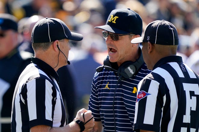 Michigan head coach Jim Harbaugh, center, questions a call during the first half.