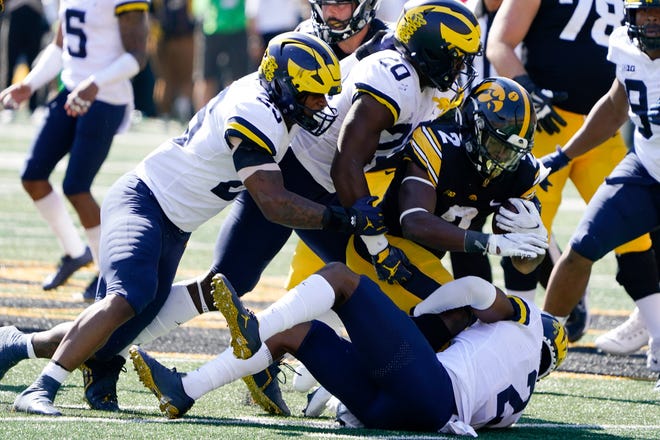 Iowa running back Kaleb Johnson, center, is tackled by Michigan linebacker Junior Colson, left, Kalel Mullings and defensive back Will Johnson, right, during the second half.