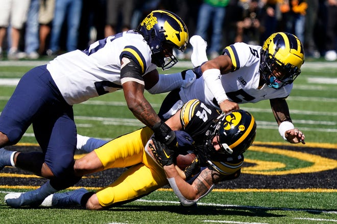 Iowa wide receiver Brody Brecht (14) is tackled by Michigan linebacker Junior Colson, left, and defensive back DJ Turner (5) after catching a pass during the first half.