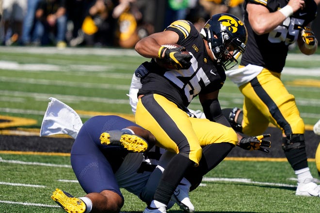 Iowa running back Gavin Williams (25) is tackled by Michigan linebacker Taylor Upshaw (91) after catching a pass during the first half.