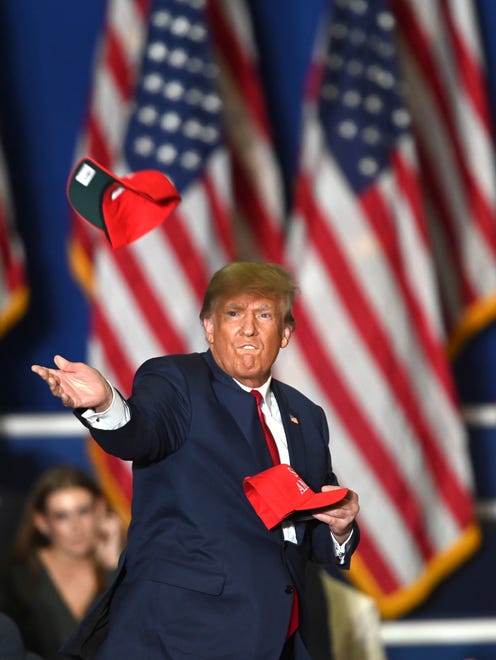 President Donald Trump throws Save America hats to the crowd as he enters the Macomb County Community College Sports and Expo Center in Warren, Saturday, October 1, 2022.