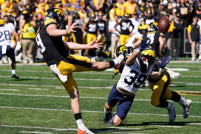 Michigan's Joe Taylor (39) tries to block a punt by Iowa punter Tory Taylor (9) during the first half.