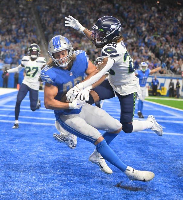 Lions' T.J. Hockenson hangs onto a touchdown reception with Seahawks' Ryan Neal defending in the fourth quarter.