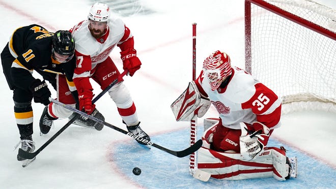 Detroit Red Wings goaltender Ville Husso (35) drops to the ice to make a save on rebound by Boston Bruins center Trent Frederic (11) during the first period of an NHL hockey game, Thursday, Oct. 27, 2022, in Boston. At center is Detroit Red Wings defenseman Filip Hronek.