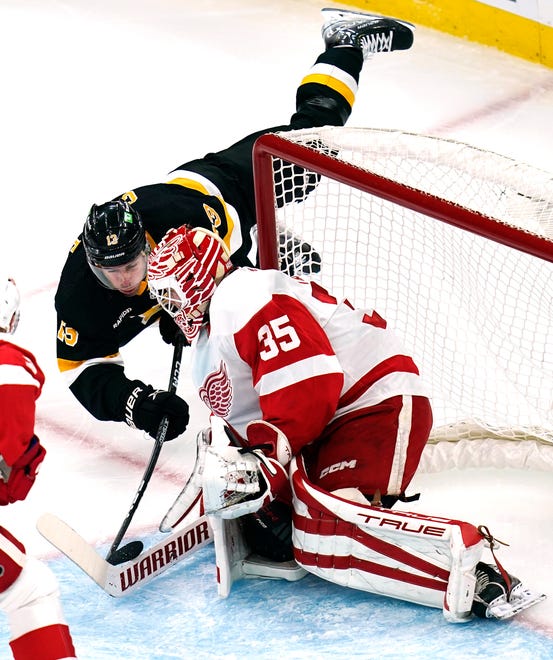 Boston Bruins center Charlie Coyle dives forward on a shot from behind Detroit Red Wings goaltender Ville Husso (35) during the first period of an NHL hockey game, Thursday, Oct. 27, 2022, in Boston.