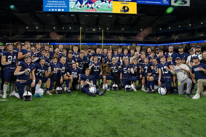 Grand Rapids South Christian players gather with the Division 4 state football championship trophy.
