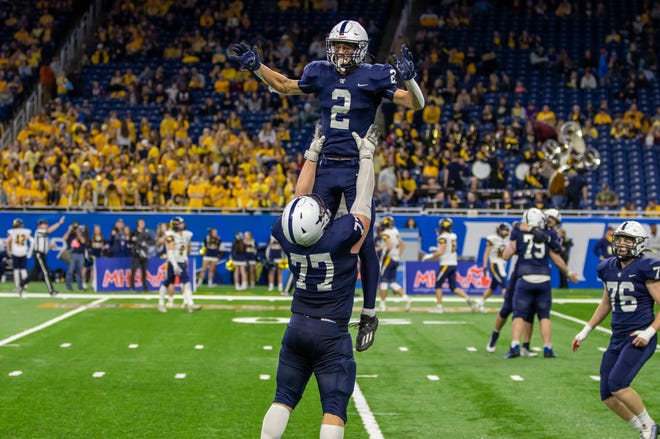 Grand Rapids South Christian's Cam VanSolkema (77) hoists Jake Vermaas after his pick-six put a cap on a 28-0 Division 4 state finals victory.