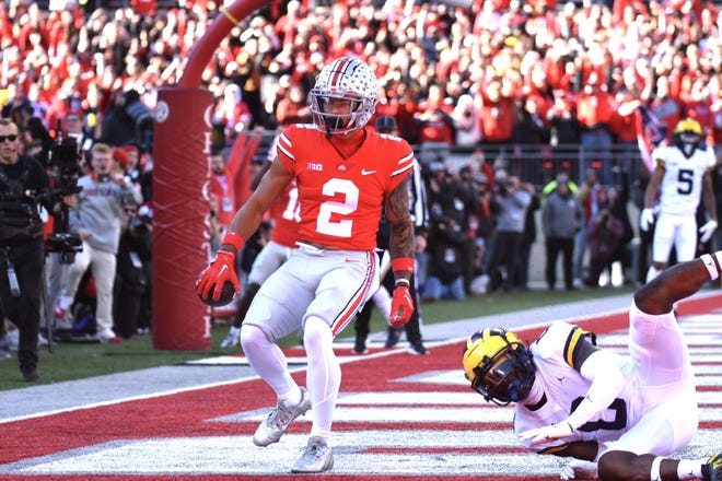 Ohio State's Emeka Egbuka (2) catches the game's first touchdown as he's covered by Michigan's Mike Sainristil (0) in the first quarter.