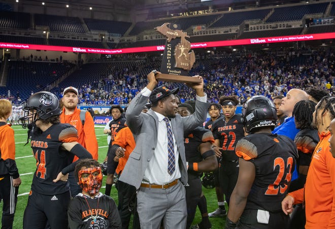 Belleville interim head coach DeJuan Rogers hoists the Division 1 state championship trophy after beating Caledonia, 35-17, at Ford Field in Detroit on Saturday, Nov. 26, 2022.