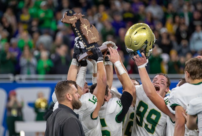 Jackson Lumen Christi players hoist the Division 7 state championship trophy after defeating Traverse City St. Francis, 15-12, at Ford Field in Detroit on Saturday, Nov. 26, 2022.