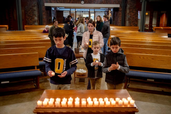 Oxford, Mich., resident Laurie Bolognesi and her sons, from left, Luca, 13, Leo, 7, and Giammarc, 10, light votive candles in remembrance of the Oxford school shooting, Wednesday, Nov. 30, 2022, at St. Joseph Catholic Church in Lake Orion, Mich.