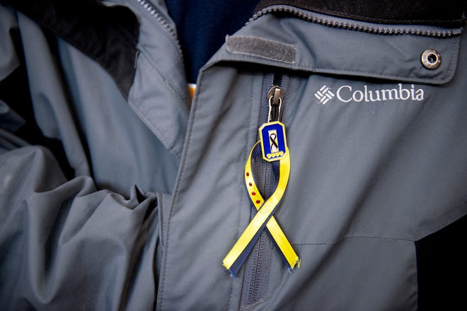 An Oxford resident wears an Oxford strong ribbon pin to honor the lives of the four slain students, six injured students, one injured teacher as well as staff and first responders at a service on Wednesday, Nov. 30, 2022 at ST. Joseph Catholic Church in Lake Orion.