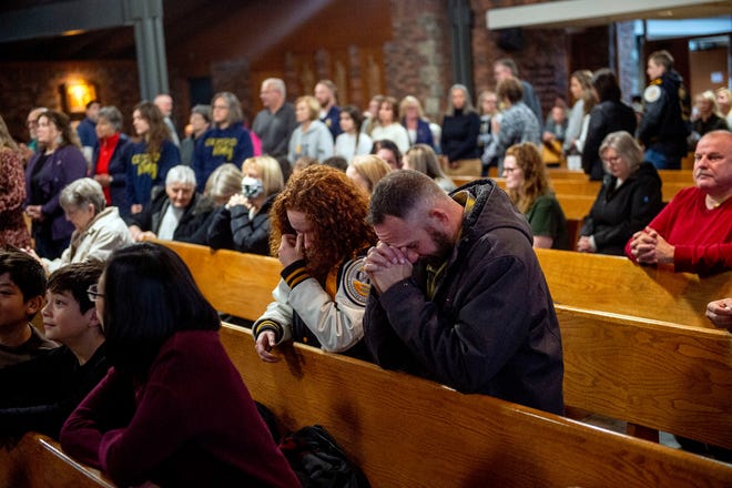 Oxford, Mich., resident Kevin Feeney kneels and prays alongside his daughter Avery, a junior at Oxford High School, Wednesday, Nov. 30, 2022, at St. Joseph Catholic Church in Lake Orion, Mich.