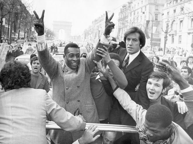In this March 30, 1971 file photo, Brazil's soccer player Pele flashes victory signs as he rides down the Champs Elysees on his way to a reception at the Town Hall in Paris, France.