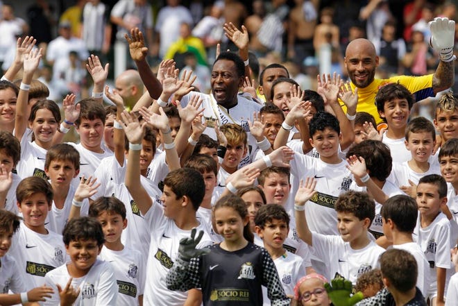 Pele, center top, and his son Edson Cholbi do Nascimento, above at right, wave with children during during the centennial anniversary celebration of the team in Santos, Brazil, April 14, 2012.