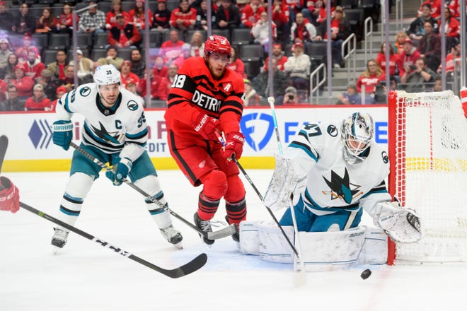 Detroit center Andrew Copp tries to get the puck past San Jose center Logan Couture, left, and goaltender James Reimer during the first period of a game between the Detroit Red Wings and the San Jose Sharks at Little Caesars Arena, in Detroit, Jan. 24, 2023.