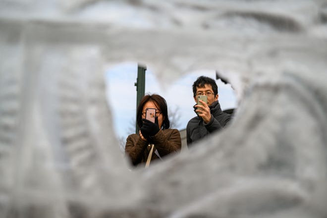 Visitors walk past the ice carvings during the Plymouth Ice Festival in Plymouth, February 5, 2023.