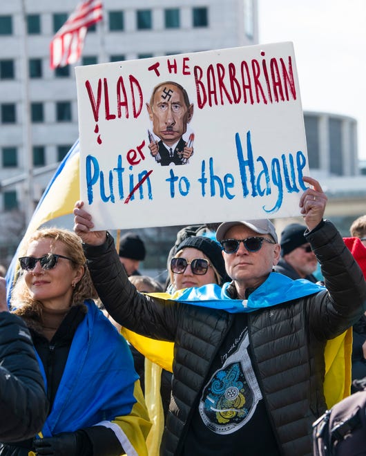 Nick Deychakiwsky of Brighton holds an anti-Putin sign made by Oksana Pronych, left, also of Brighton, during a ÔStand With UkraineÕ flashmob and rally in Detroit on Sunday, February 27, 2022. The event was organized by the Ukrainian-American Crisis Response Committee of Michigan.